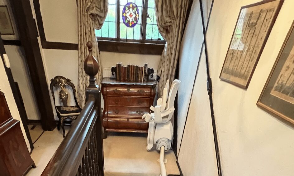 Curved Stairlift Model on Straight Stairs - Case Study (Otolift Modul-Air Smart) - Kudos Stairlifts blog header image, stairlift at top of stairs with seat folded